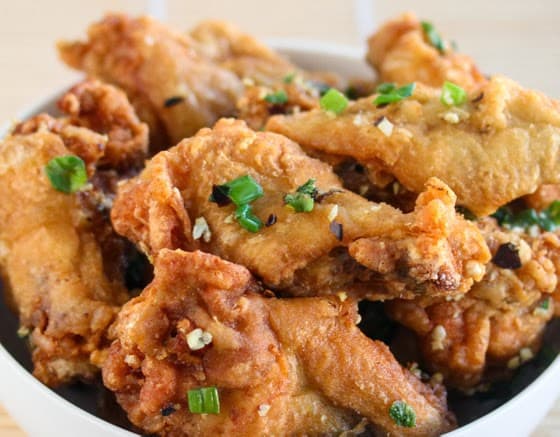 Bowl of low-carbohydrate fried chicken wings garnished with scallions